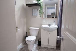 a white bathroom with a toilet and a sink at RiversTail Retreat Pet-Friendly and Steps to The Lake in Harrison Hot Springs