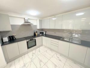 ミッチャムにあるSpacious 6-bedroom house in South London (Zone 4)の白いキッチン(白いキャビネット、シンク付)