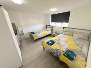 ミッチャムにあるSpacious 6-bedroom house in South London (Zone 4)のベッドが2つと大きな窓がある寝室 +17枚の写真