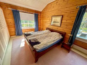 ein Schlafzimmer mit einem Bett in einem Holzzimmer in der Unterkunft Villa Mustikka - Modern Log Villa on a Waterfront Estate in Långstrand
