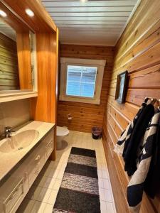 ein Holzbadezimmer mit einem Waschbecken und einem WC in der Unterkunft Villa Mustikka - Modern Log Villa on a Waterfront Estate in Långstrand
