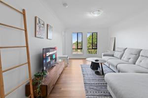 ブリスベンにあるSunnybank Hills Spacious 5BR Home for Familiesのソファとテーブルのあるリビングルーム