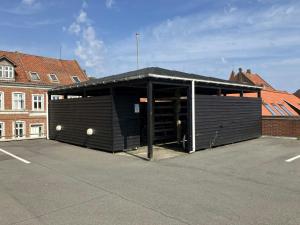 ein schwarzes Gebäude mit offener Tür auf einem Parkplatz in der Unterkunft Central Studio for 1 in Fredericia