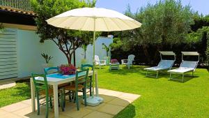 a table and chairs with an umbrella in a yard at Il Bounty - struttura per soggiorni brevi - in Fontane Bianche