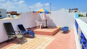 a patio with chairs and an umbrella on a roof at Maison de la Lagune in Oualidia