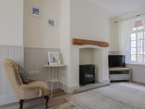 a living room with a chair and a fireplace at Belfry Cottage in Colyton