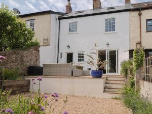 a white house with a garden in front of it at Belfry Cottage in Colyton