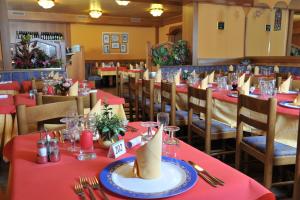 uma sala de jantar com mesas e cadeiras com toalhas de mesa vermelhas em Hotel Negritella em Passo del Tonale