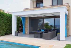 an expandable pergola over a patio with a pool at Pentanemi Luxury Villa in Hanioti +20 photos
