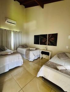 Una habitación con tres camas y un televisor en la pared. en Estância do Sol, en Pirenópolis 18 fotos más