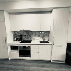 una cucina con mobili bianchi e un forno a piano cottura di Chic Retreat Pet & Smoke-Friendly, Balcony Views, Prime Location a Vaughan