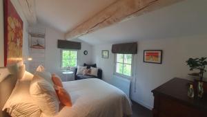a bedroom with a bed with white sheets and windows at Lou Pantai, Bed and Breakfast, double room in Aix-en-Provence