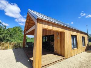 a large wooden building with a large open door at Le chalet de Joyce spa et piscine in Saint-Aubin-des-Préaux