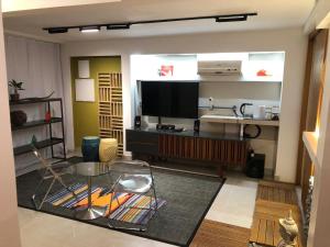 a living room with a flat screen tv and a table at Quarto equipado Centro Balneário Camboriú in Balneário Camboriú