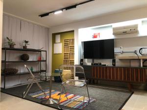 a living room with a television and a table and chairs at Quarto equipado Centro Balneário Camboriú in Balneário Camboriú