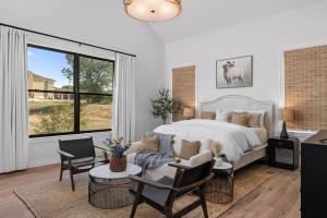 een slaapkamer met een bed en een groot raam bij Calivence Haus - Estate Home in Fredericksburg