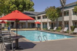 a pool with chairs and a table with an umbrella at Best Western Heritage Inn in Concord