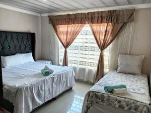 a bedroom with two beds and a window at Newview bnb and spa in Thulamahashi