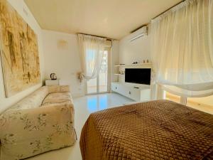 una camera da letto con un letto, un divano e una televisione di Mora Suite a Bari