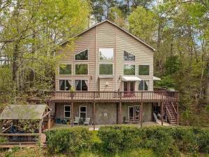 a large house with a porch and a deck at Lakeshore Retreat with Lake Lanier views & hot tub in Landrum
