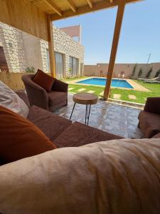 a living room with a couch and a table and a pool at Stone Kaouki's House in Sidi Kaouki