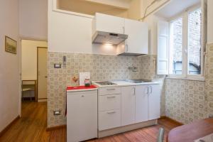 una pequeña cocina con armarios blancos y una ventana en Navona Tower Relais, en Roma