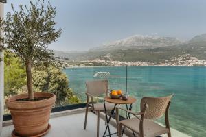 a table and chairs on a balcony with a view of the water at Njivice Coastal Oasis in Njivice