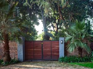 a fence with a wooden gate with palm trees at Waters on Willows in Pretoria