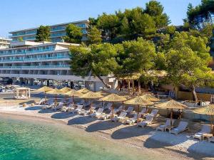 a beach with chairs and umbrellas and a building at Apartman Sea in Podstrana