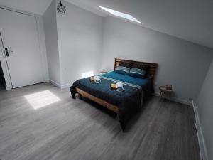 a bedroom with a blue bed in a white room at La Maison de Pandora in Maulévrier