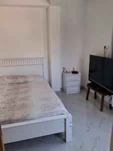 a bedroom with a bed and a flat screen tv at Casa da Sara Guest House in Mindelo
