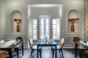 een eetkamer met 2 tafels en stoelen en 2 ramen bij Villa Vasco da Gama in Cascais