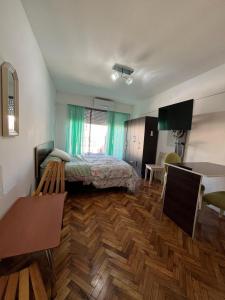 Un dormitorio con una cama y suelo de madera. en Luminoso y Cálido con Balcón a la calle, en Buenos Aires 1 foto más