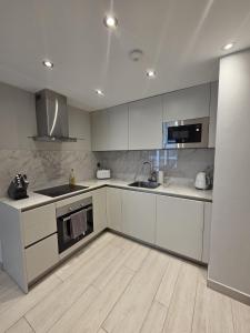 ジブラルタルにあるLuxury Marina Apartment, Pool, Views & Prime Locationのキッチン(白いキャビネット、シンク、コンロ付)
