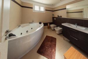 ein Badezimmer mit einer großen Badewanne, einem Waschbecken und einem WC in der Unterkunft Roda Luxury Beach House in Roda + 29 Fotos