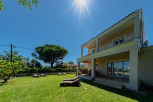ein Haus mit einer Liegewiese mit Liegestühlen im Hof in der Unterkunft Roda Luxury Beach House in Roda