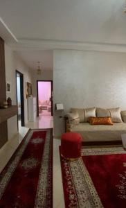 a living room with a bed and a red rug at Appartement meublé en location nuitée in El Jadida