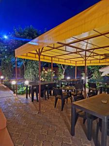 a patio with tables and chairs under a yellow umbrella at Vila Tropical in Costinesti