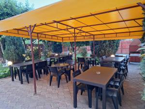 a patio with tables and chairs under a yellow umbrella at Vila Tropical in Costinesti +36 photos