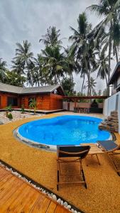 a large swimming pool with two chairs and a house at Casa Di Legno Resort in Salalah +17 photos