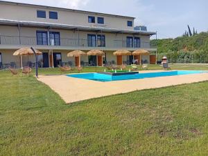 a building with a pool and chairs and umbrellas at Bella Kaliva in Kalives Poligirou