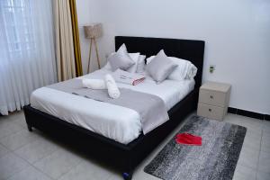 a bedroom with a bed with white sheets and pillows at Cozy Homes in Nakuru