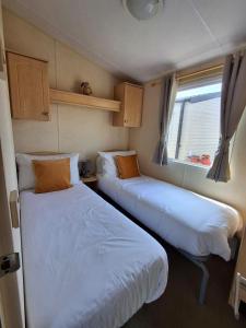 zwei Betten in einem kleinen Zimmer mit Fenster in der Unterkunft Wonderful 6 Berth Caravan In Norfolk At Heacham Beach, Ref 21012E in Heacham