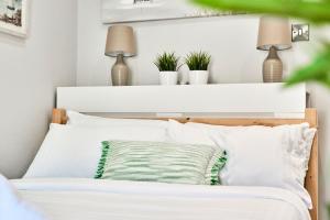 ein Schlafzimmer mit einem Bett mit weißen Kissen und zwei Lampen in der Unterkunft Princess Blue 3 ~ Portrush by the Sea in Portrush