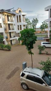un coche aparcado en un estacionamiento junto a un árbol en Marie's 2 bed all-ensuite Milimani ksm, en Kisumu