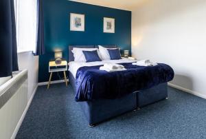 een slaapkamer met een groot bed met blauwe muren bij Cambridge House near Addenbrookes, parking and WiFi! in Shelford