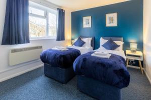 two beds in a room with blue walls at Cambridge House near Addenbrookes, parking and WiFi in Shelford