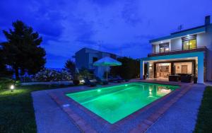 a swimming pool in front of a house at night at Pentanemi Luxury Villa in Hanioti
