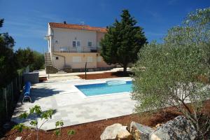 a backyard with a swimming pool and a house at Olive Apartments in Ugljan