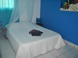a white bed with a purple towel on it at CoCoKreyol - " ARUBA" in Les Trois-Îlets